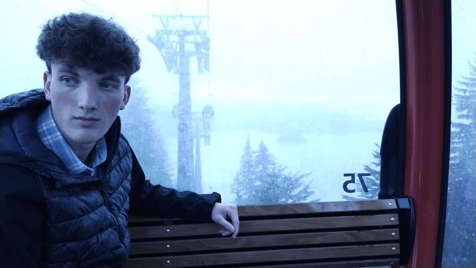 Man sitting on ski lift with snow in the background